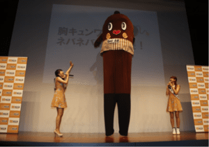 Two Miss Natto contestants pose with natto mascot Natto Nebaaru-kun