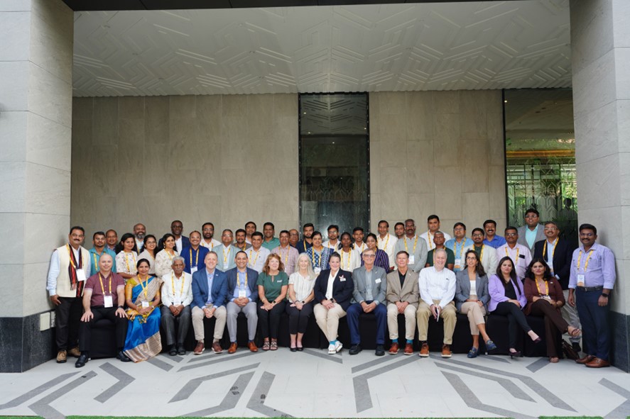 A large group of agribusiness professionals pose outside of a center