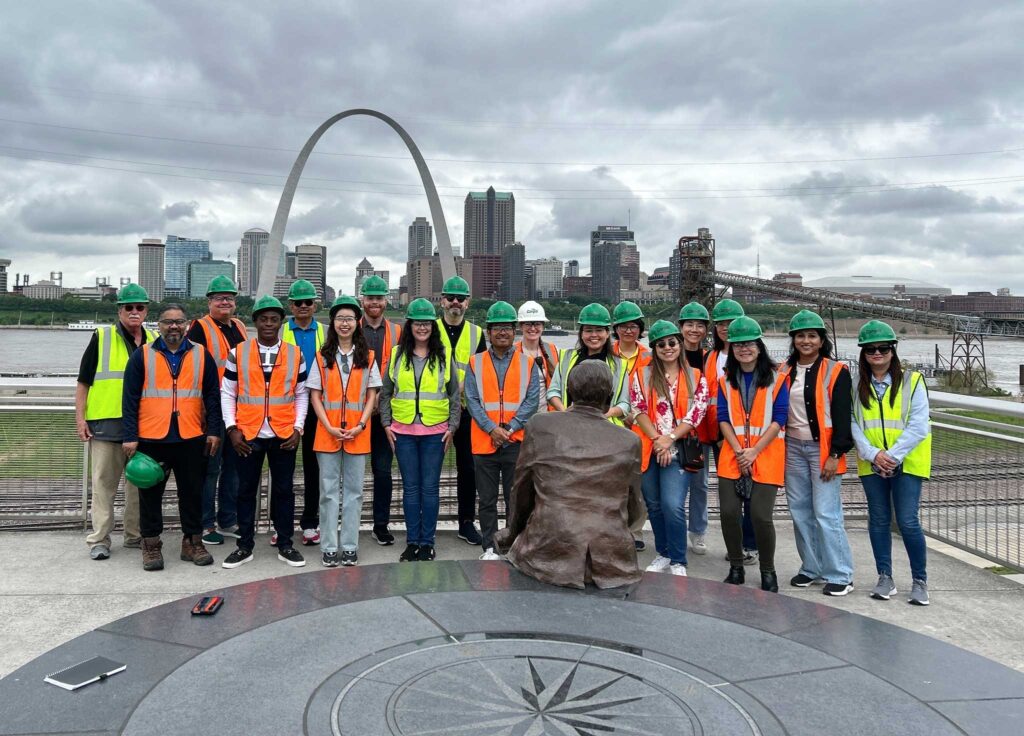 A group of team members in safety vests and hard hats with the St. Louis arch in the background